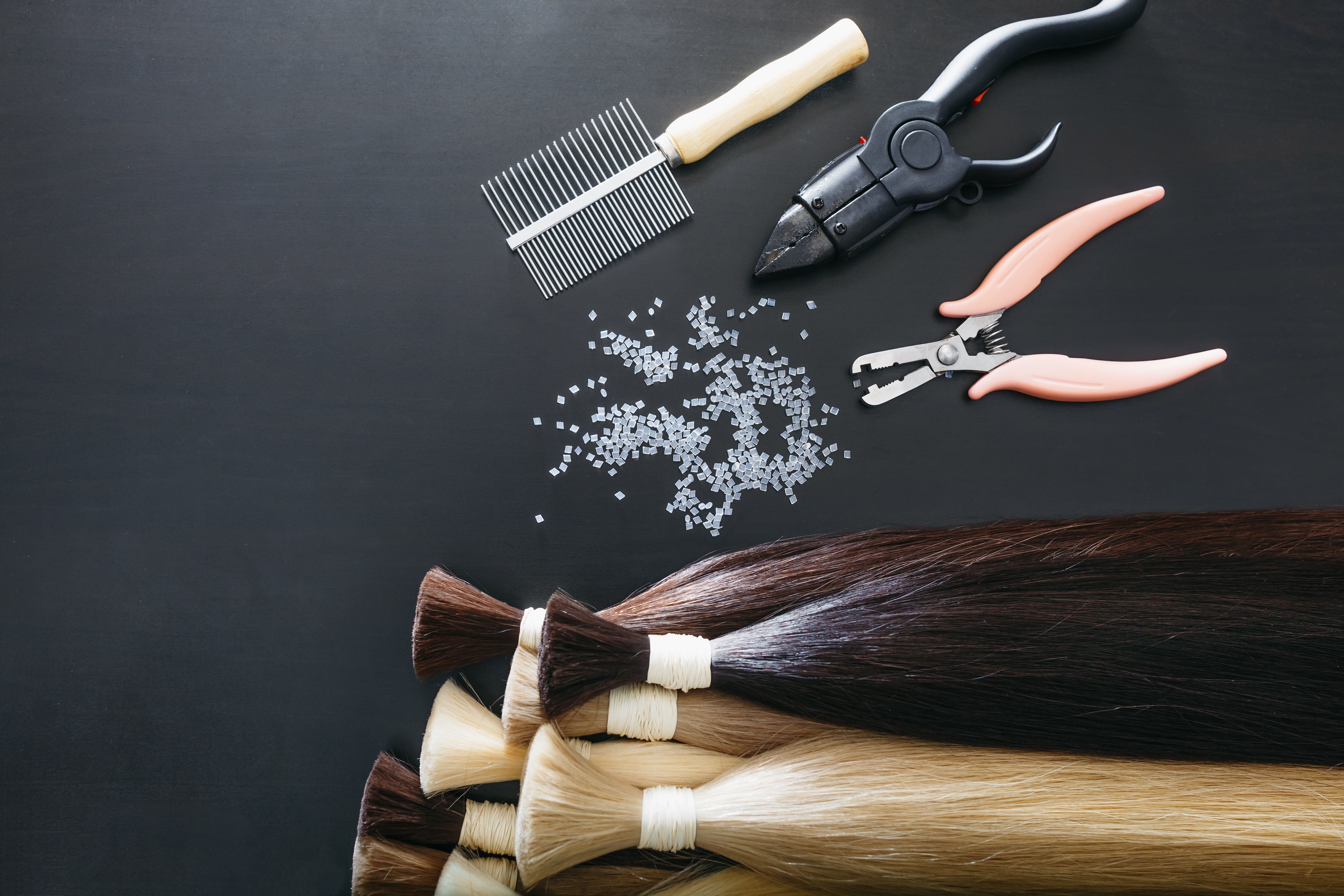 Hair extensions and styling tools on a dark background
