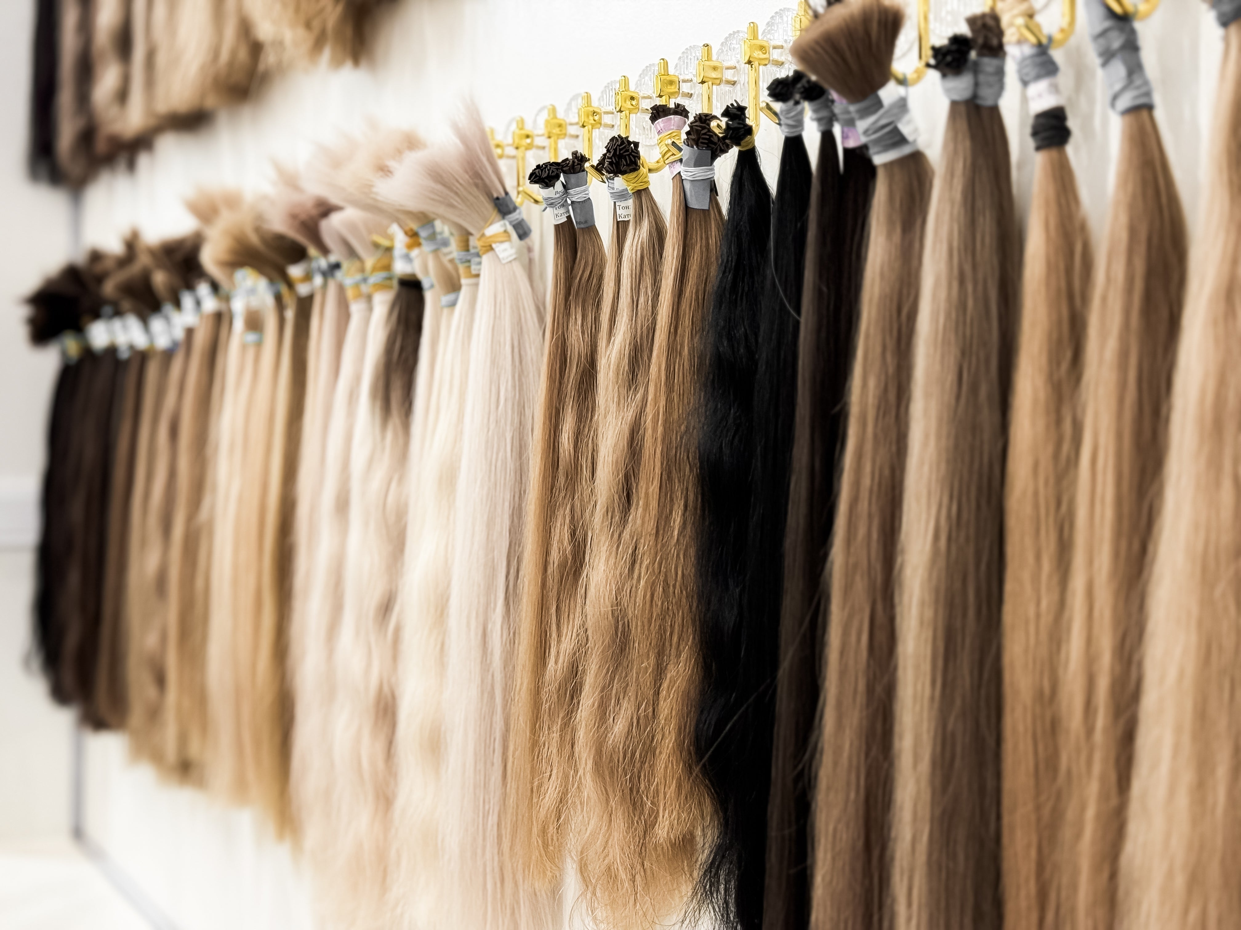 Row of hair extensions in various colors on a rack.