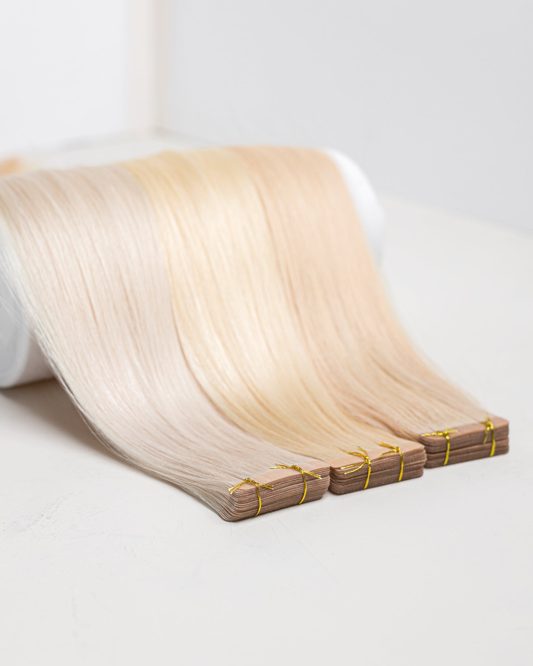 A bundle of Russian blonde tape hair extensions laid out on a flat surface. 50g remy Human Hair