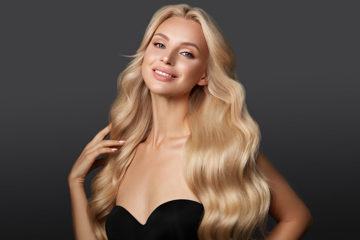 Woman with long, wavy blonde hair against a dark background